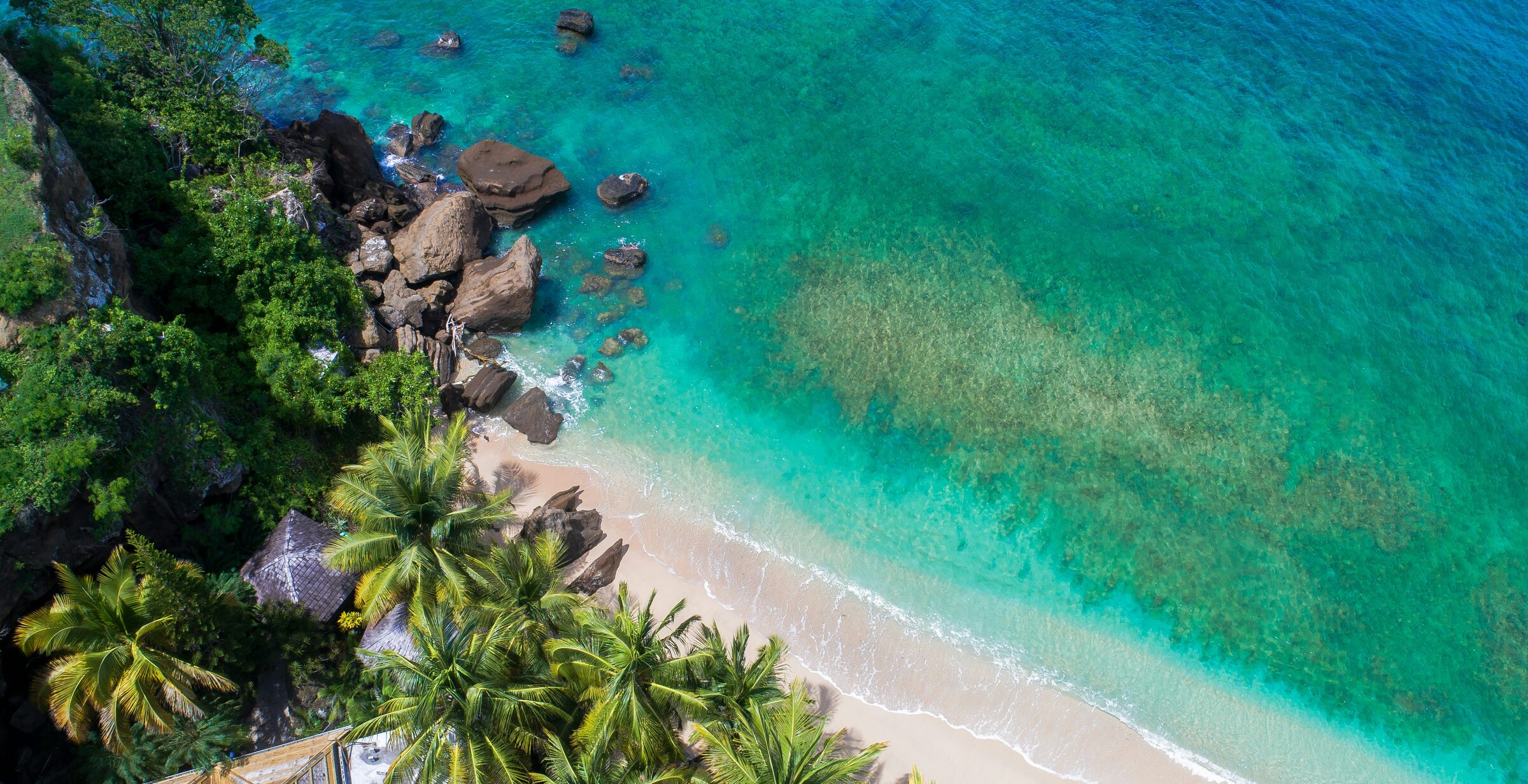 Aerial view of a quiet Grenada beach with granite boulders and clear turquoise water