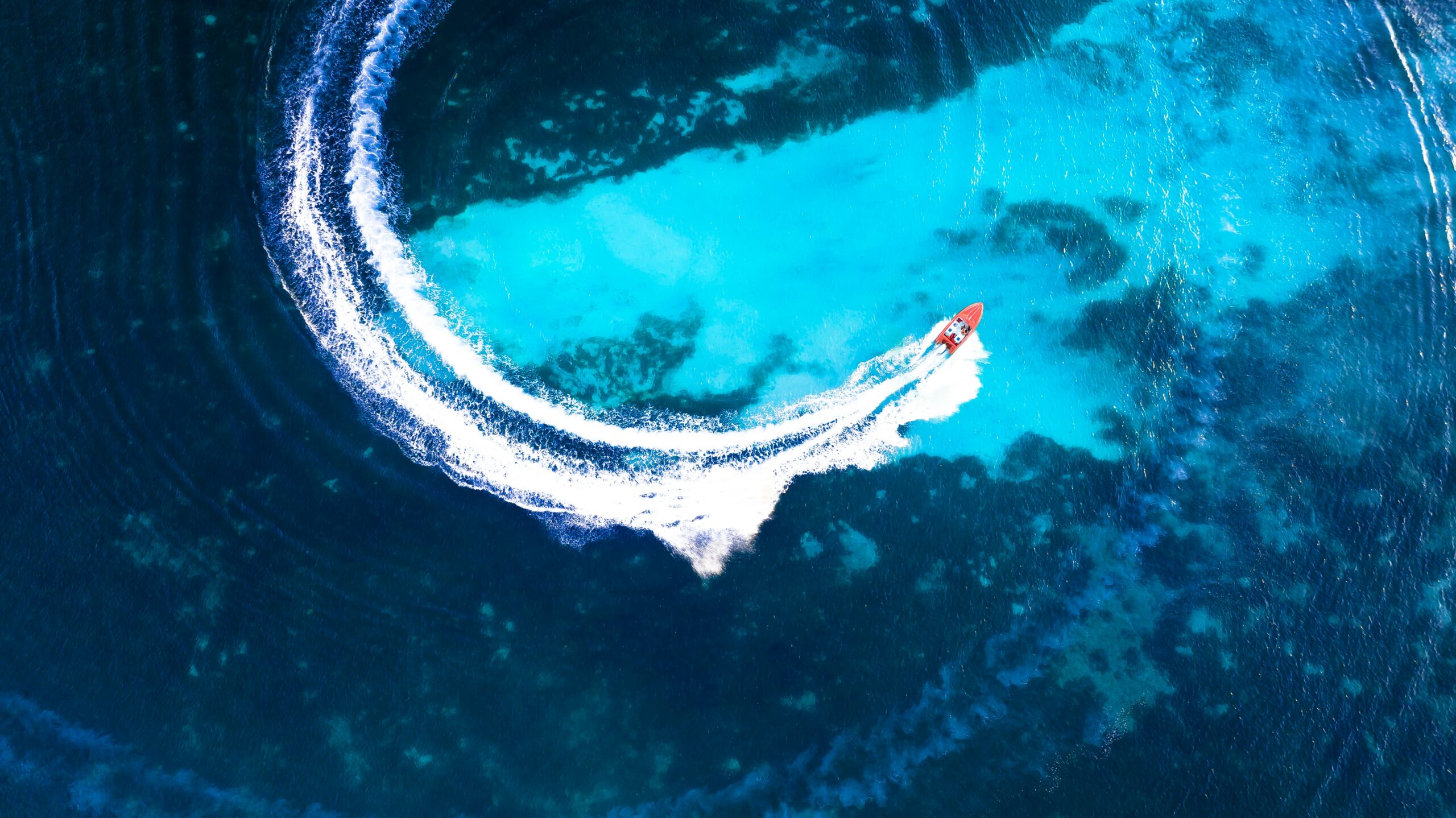A speedboat carving a white wake through deep blue water off Grenada