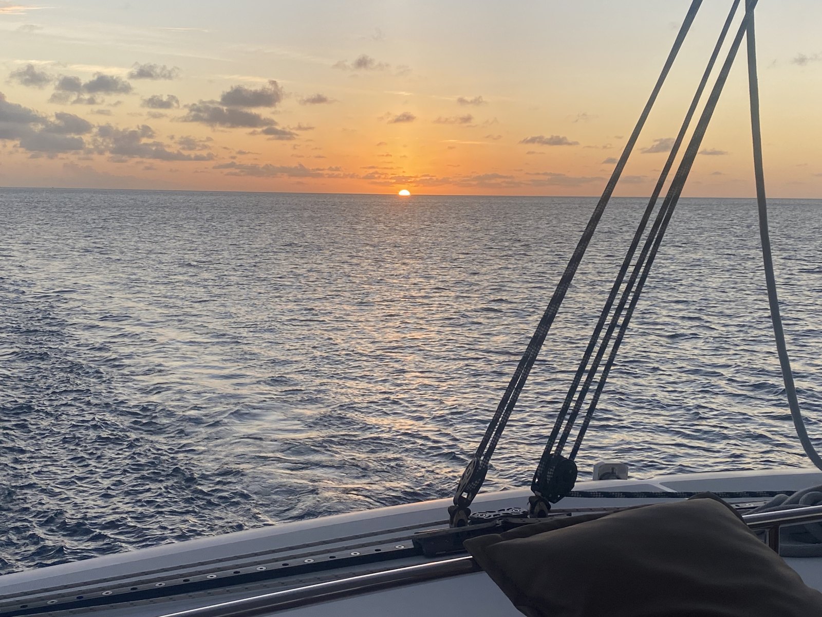 The sun setting over calm water, seen past the rigging of a yacht off Grenada