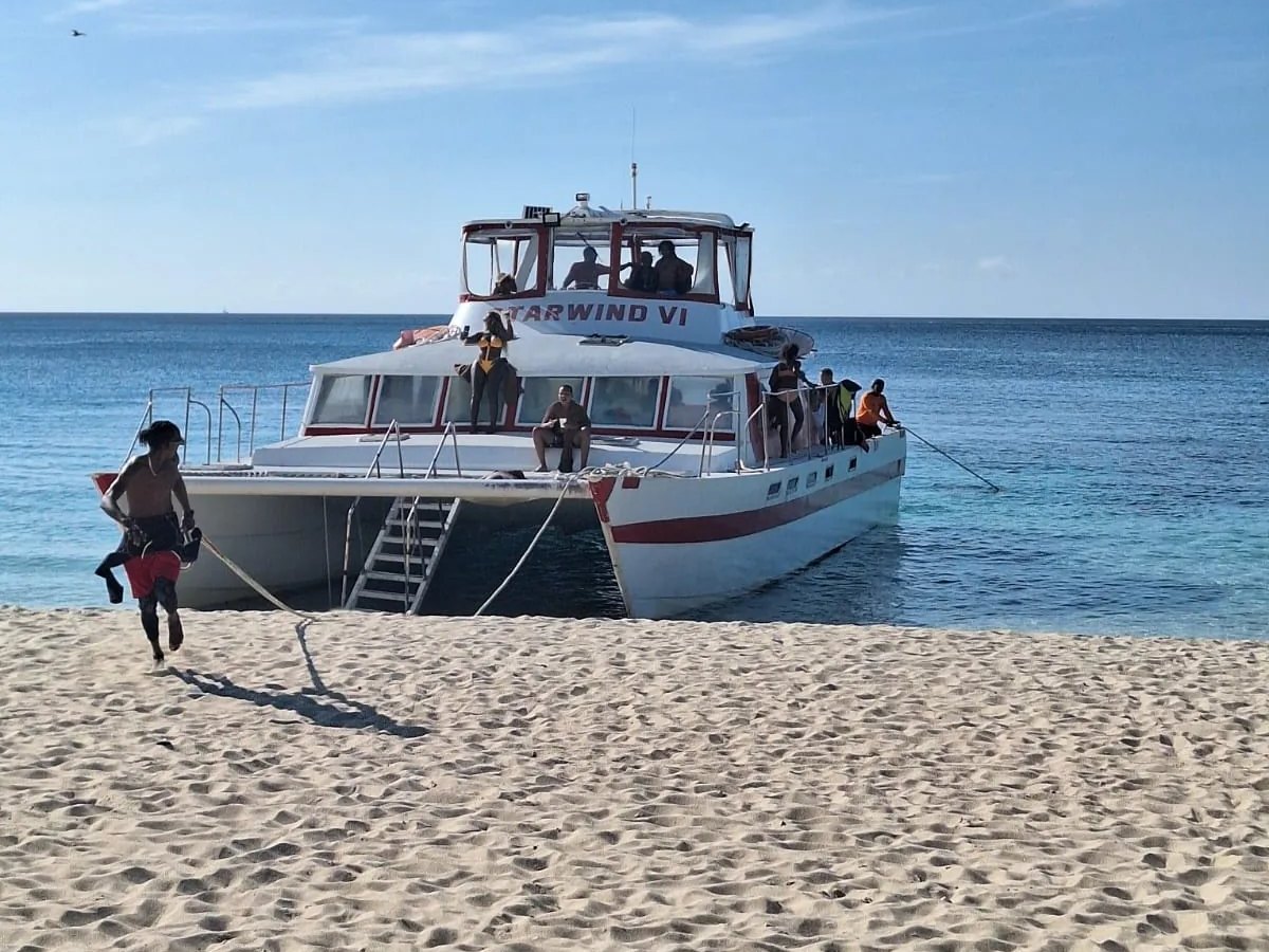 Starwind VI beached on soft sand with a crew member running the line ashore