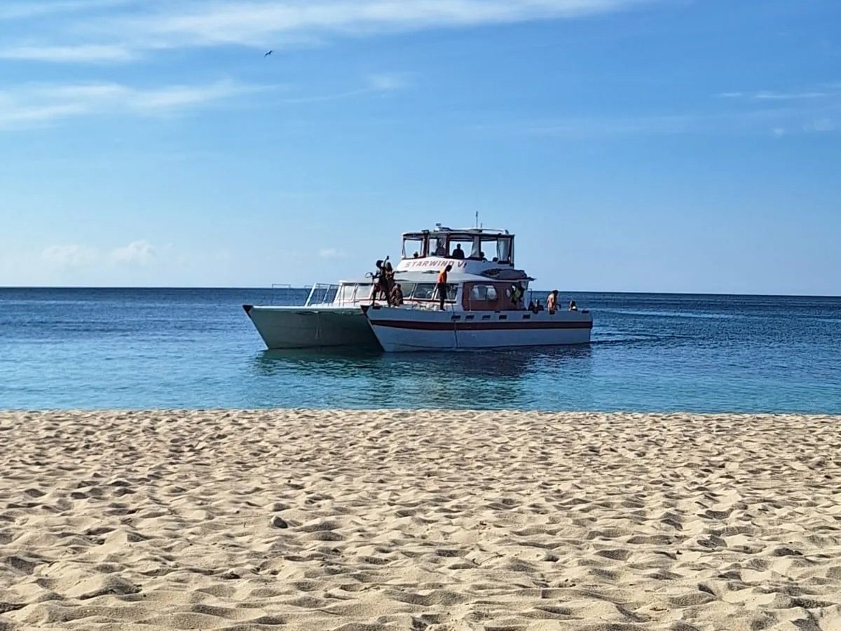 Starwind VI anchored off a beach on calm blue water